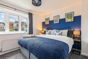 a bedroom with a large bed with blue walls and windows at Contractor Base Parking 4 Beds Fast Wi-Fi in Bolton upon Dearne