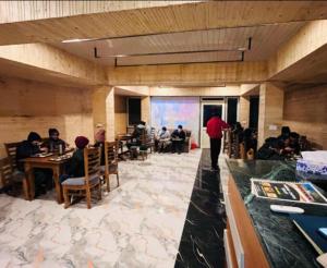 a group of people sitting at tables in a restaurant at Himrab Chopta Resort in Chopta