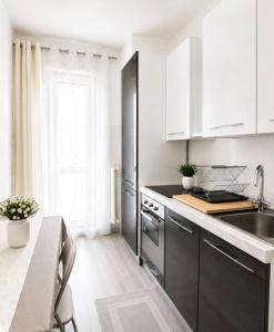 a kitchen with white cabinets and a black refrigerator at Liam House - Stanza 1 in Limbiate