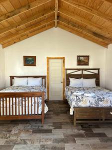 two beds in a room with wooden ceilings at #11- Rancho Meling in Camalú