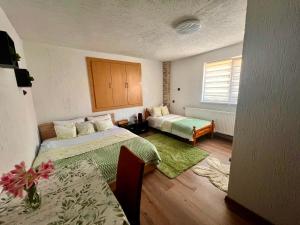 a hotel room with two beds and a table and a table sidx sidx at Къща за гости Шанови in Gʼovren