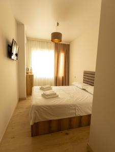a bedroom with a bed with white sheets and a window at Mos House in Kobuleti
