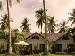 a white house with palm trees and an umbrella at Rodeo Sun Hotel in General Luna