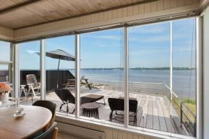 a screened in porch with a view of the water at LF15135-Farso-Strandvejen-35-B in Hvalpsund