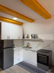 a kitchen with white cabinets and a black refrigerator at ZELENI BOR koliba vikendica Pale in Pale