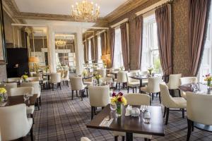 a restaurant with tables and chairs and a chandelier at Belmont House Hotel in Banbridge