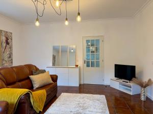 a living room with a couch and a flat screen tv at Casa do Rio Ceira Góis in Góis