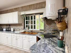 a kitchen with white cabinets and a marble counter top at Casa do Rio Ceira Góis in Góis