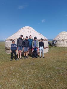 a group of people standing in front of a yurt at Sonkol-resort in Song-Kul