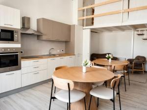 two tables and chairs in a kitchen with white cabinets at La Via Per Erice in Casa Santa