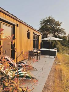a house with a patio with a table and an umbrella at Tiny House mit Whirlpool und Sauna in Bermel