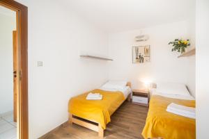 two beds in a small room with yellow sheets at Gwarek Ośrodek nad Morzem Pokoje z wyżywieniem in Międzywodzie