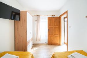 a room with two beds and a television and a door at Gwarek Ośrodek nad Morzem Pokoje z wyżywieniem in Międzywodzie