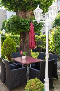 einen Tisch und Stühle mit einem roten Regenschirm und einem Baum in der Unterkunft Ferienwohnungen am Wintergarten in Gera