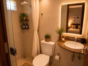 a bathroom with a toilet and a sink and a mirror at Hotel Copacabana Stay in Serra
