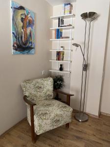 a chair and lamp in a room with a book shelf at Macskakő Apartman in Szentendre