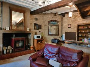 a living room with a leather couch and a fireplace at MUSIROSA in Vézelay