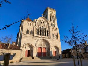 a large church with a tall tower with red doors at MUSIROSA in Vézelay +17 photos