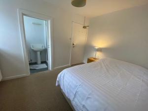 a bedroom with a bed and a bathroom with a sink at The Bognie Inn in Huntly