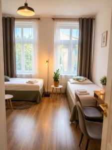 a room with two beds and a desk and windows at Gdańsk in Gdańsk