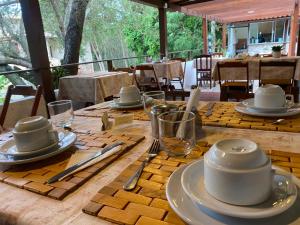 a wooden table with plates and utensils on it at Pousada Oceanica Buzios in Búzios