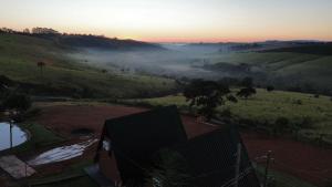 a view of a foggy field with a house at Chalés JH Serra da Canastra in São Roque de Minas