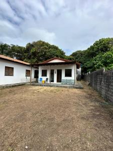 a small white house with a dirt road in front at Nosso Chalé in Marapanim