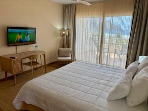 a bedroom with a large white bed and a television at Lam Hotel Foya Branca in São Pedro +40 photos