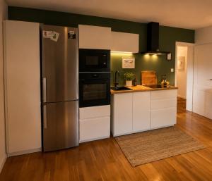a kitchen with a stainless steel refrigerator and white cabinets at Ferienwohnung Eifelglück in Pelm
