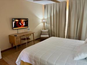 a bedroom with a bed and a desk with a television at Lam Hotel Foya Branca in São Pedro