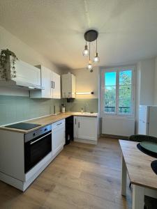 a kitchen with white cabinets and a table and a window at L'Echappée Belle in Paray-le-Monial
