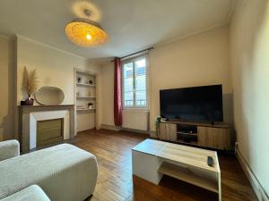 a living room with a flat screen tv and a couch at L'Echappée Belle in Paray-le-Monial