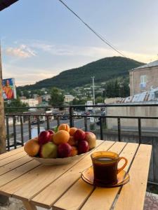 a bowl of fruit on a wooden table with a cup of coffee at Noyemberyan Central Apartment in Noyemberyan