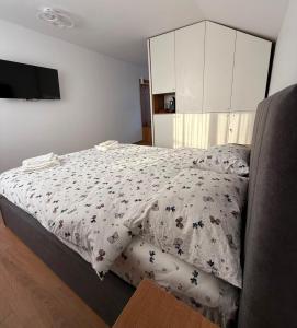 a bedroom with a bed with a comforter on it at Luca Rooms in Curtea de Argeş