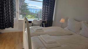 a bedroom with two beds and a desk and a window at Húsavík Apartment in Húsavík