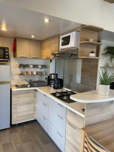 a kitchen with white cabinets and a white microwave at Le Soléa in Le Cailar +13 photos