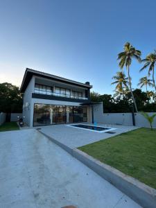 a large house with a large driveway and palm trees at Casa 03 suites Maragogi Japaratinga in Japaratinga