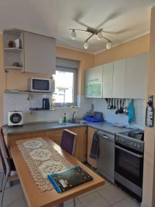 a kitchen with white cabinets and a wooden table at Apartmani Bozenov in Petrovac na Moru