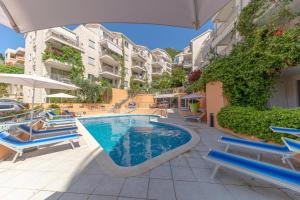 a swimming pool with blue chairs next to a building at Apartmani Bozenov in Petrovac na Moru