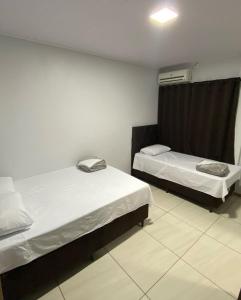 a room with two beds and a window in it at Hotel Villa Real in Pôrto Britânia