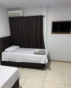 a small room with two beds and a window at Hotel Villa Real in Pôrto Britânia