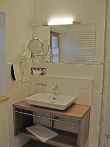 W łazience znajduje się umywalka i lustro. w obiekcie Mammhofer Suite & Breakfast w mieście Oberammergau
