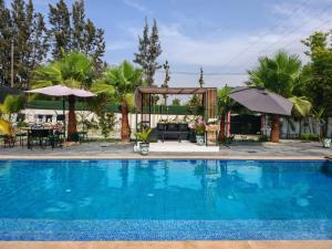 a swimming pool with a table and an umbrella at Villa Aronora in Rabat