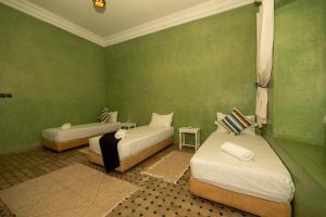 two beds in a room with green walls at Villa Dar Luz in Marrakesh