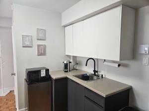 a small kitchen with a sink and a microwave at Where Comfort Meets Cozy Vibes in Montreal