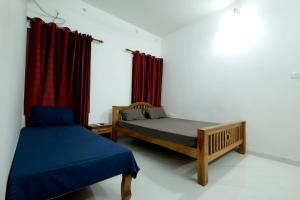 a bedroom with two beds and a red curtain at MeadowView Cottage Marari in Mararikulam