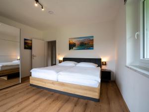 a bedroom with a bed with white sheets and a mirror at RABENSTEINER - Panorama Apartments - Bad Kleinkirchheim in Bad Kleinkirchheim