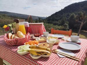 a picnic table with food on a checkered table cloth at Chalé Amanhecer in Aiuruoca +10 photos