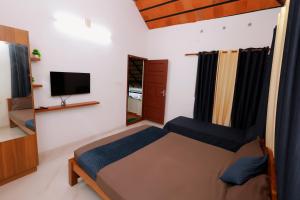 a bedroom with a bed and a flat screen tv at MeadowView Cottage Marari in Mararikulam