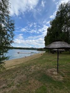 a beach with an umbrella and a body of water at Silent Jacht Solina in Polańczyk